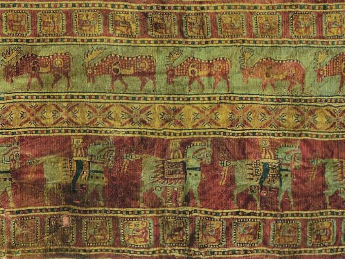 Pazyryk carpet: deer above, Saka horsemen below in pointed caps and trousers